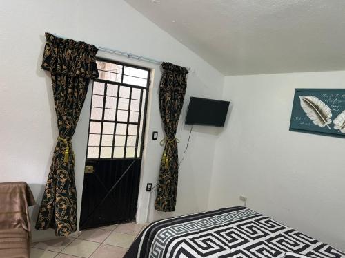 a bedroom with a bed and a door with curtains at Carpe Diem in Zacatlán