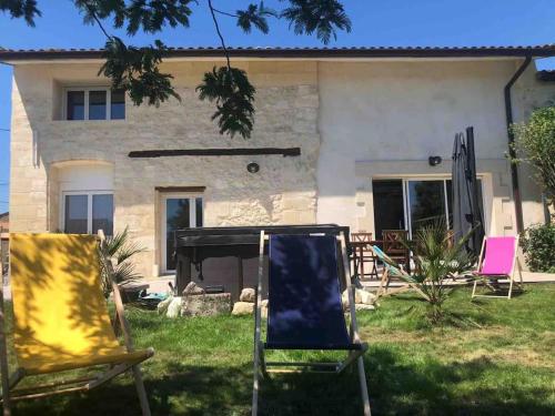 two chairs sitting in the grass in front of a house at Gîte avec spa privatif à 500m de MARGAUX in Soussans