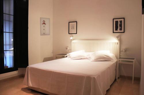 a bedroom with a large white bed with two tables at Fancy apartment in a Historic house, Chiclana City Center by C. Dreams in Chiclana de la Frontera