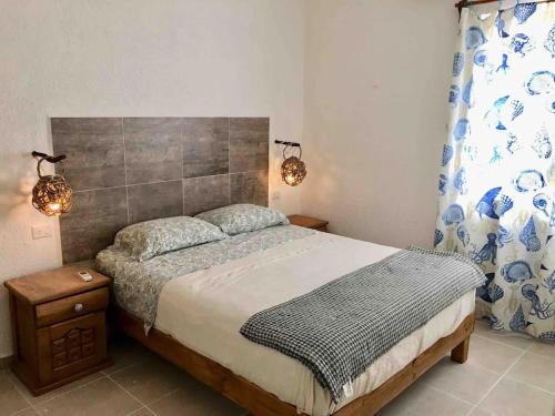 a bedroom with a bed and two lights on the wall at Casita Colibrí - An eco chic house in Mahahual
