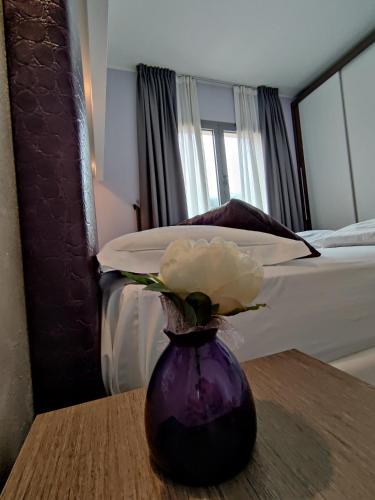 a purple vase with a flower on a table in a bedroom at Gardesana Active Apartments in Malcesine