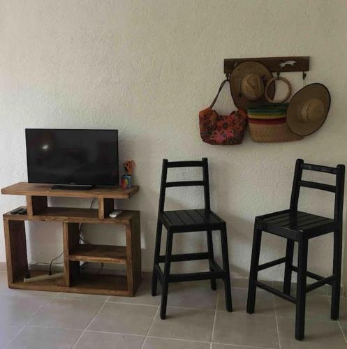 two chairs and a tv on a table with a television at Casita Colibrí - An eco chic house in Mahahual