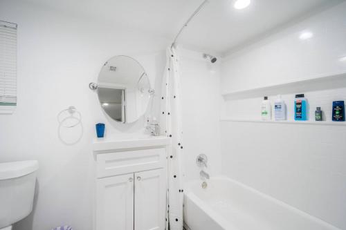 een witte badkamer met een wastafel en een spiegel bij Downtown Houston Oasis - Walk to TSU or UH in Houston
