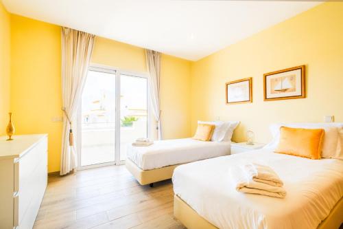 two beds in a room with yellow walls at Villa Impasse - Albufeira in Albufeira