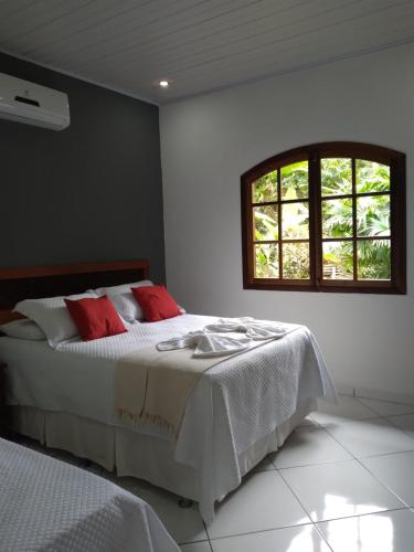 - une chambre avec un lit doté d'oreillers rouges et une fenêtre dans l'établissement Recanto da Margo 1, casa com acesso a cachoeira, à Parati