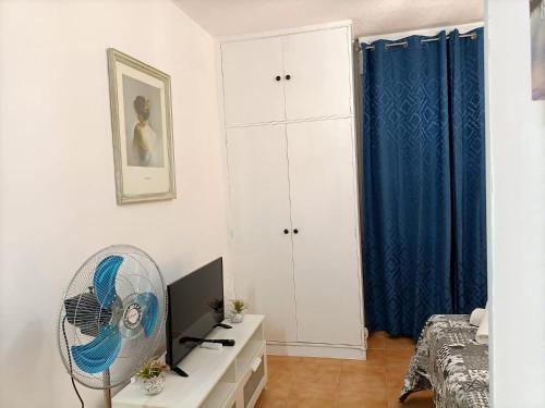 una camera con ventilatore e una camera da letto con tende blu di Estudio Exterior Gran Via Madrid W a Madrid