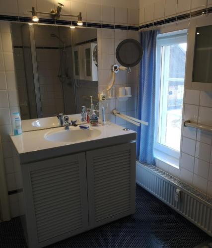 a bathroom with a sink and a mirror and a window at Ferienwohnung Apfelrose in Oldsum