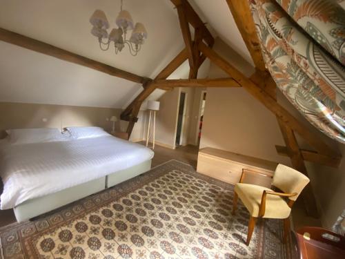 ein Schlafzimmer mit einem Bett und einem Stuhl im Dachgeschoss in der Unterkunft Pavillon d’entrée du château de Bouesse in Bouesse