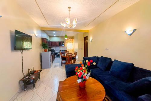 a living room with a blue couch and a table with flowers at Peace of Mind Suites in Entebbe