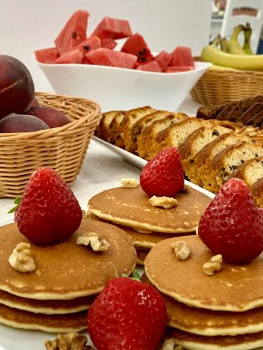 Ein Tisch voller Pfannkuchen mit Erdbeeren und Brot in der Unterkunft Hotel Tadora in Eforie Nord