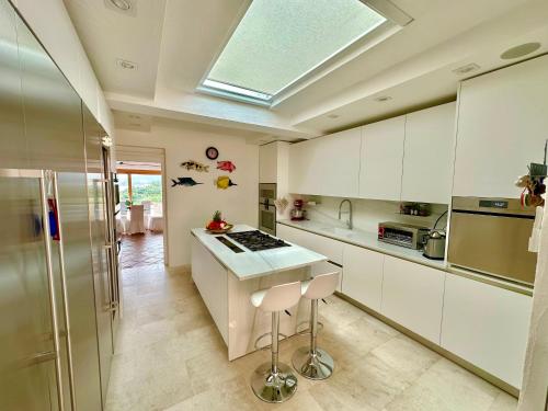 a kitchen with white cabinets and a skylight at Villa Smeralda Punta Lada Porto Rotondo in Porto Rotondo