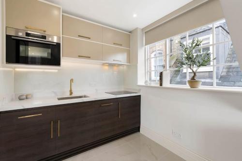 a kitchen with a sink and a microwave at Knightsbridge Apartment Mews Views, Harrods & Hyde Park in London
