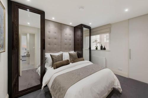 a bedroom with a large bed and a large mirror at Knightsbridge Apartment Mews Views, Harrods & Hyde Park in London