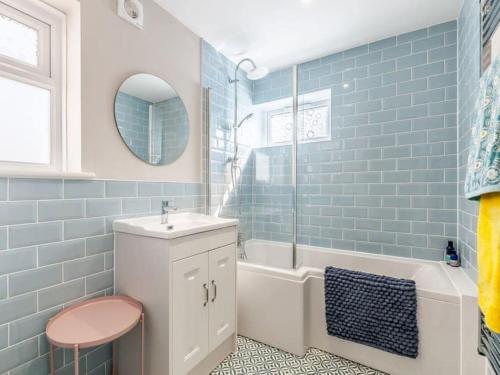 a bathroom with blue tiles and a sink and a tub at Walpole BACK House sleeps 6-8 in Margate