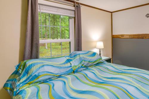 a bed with a colorful comforter in front of a window at New Concord Vacation Rental Near Kentucky Lake in New Concord