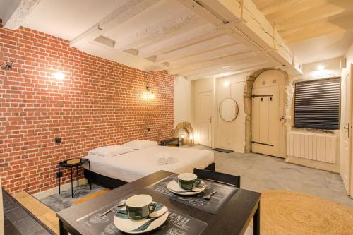 a bedroom with a bed and a brick wall at Industrial-style studio with bathtub, Vieux-Lyon in Lyon