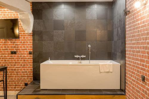 a bath tub in a bathroom with a brick wall at Industrial-style studio with bathtub, Vieux-Lyon in Lyon