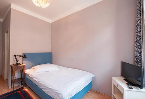 1 dormitorio pequeño con 1 cama y TV en Pension Bellevue, en Múnich