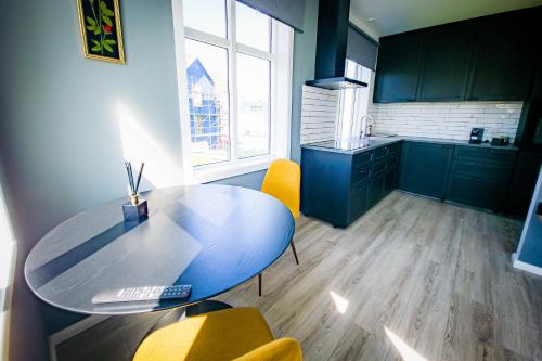 a kitchen with a blue table and yellow chairs at Guesthouse Holl in Vestmannaeyjar