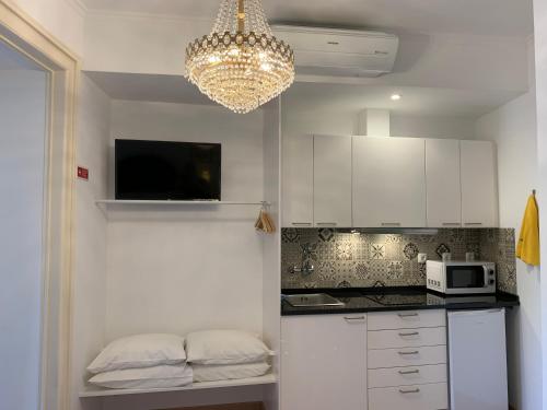 a kitchen with white cabinets and a chandelier at Discovery Apartment Estrela in Lisbon