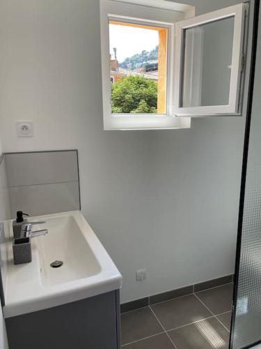 une salle de bain blanche avec un lavabo et une fenêtre dans l'établissement Grand appartement hyper centre Grasse, à Grasse
