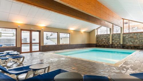 uma grande piscina com cadeiras azuis e uma mesa em 2 pièces Valloire pied des pistes em Valloire