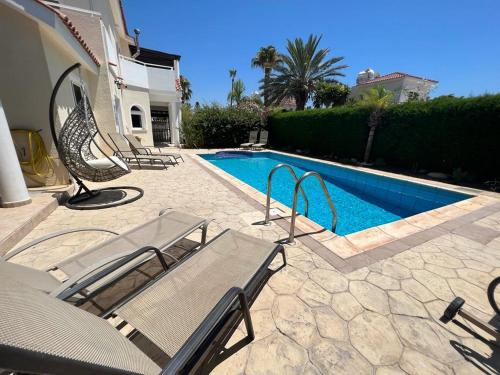 a swimming pool with chairs next to a house at Villa Tamara with Private Pool in Peyia