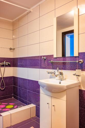 a purple bathroom with a sink and a mirror at Pensiunea Aura Deltei in Murighiol
