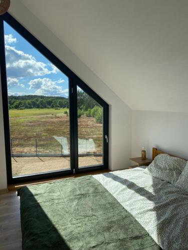 a bedroom with a large window looking out at a field at Kaszubskie Stodoły in Stara Kiszewa