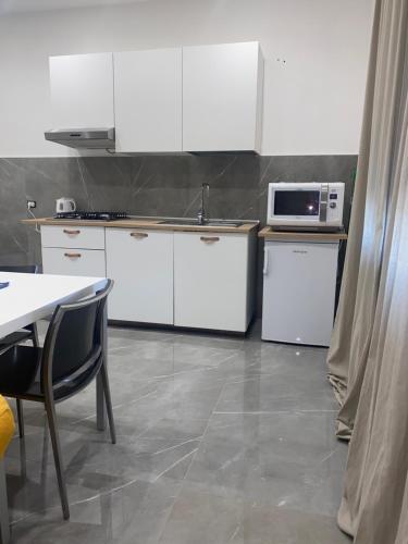 uma cozinha com armários brancos, uma mesa e um micro-ondas em Casa del Credente em Madonna dellʼArco