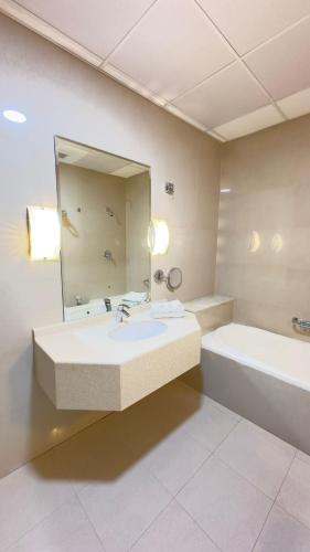 a bathroom with a sink and a tub and a mirror at القصر العالي للوحدات السكنية المفروشة in Al Khobar