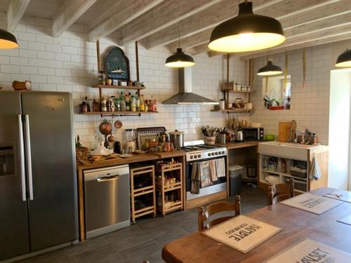 a kitchen with a refrigerator and a table in it at Découverte d'un Haras proche du Mont St Michel in Hambye