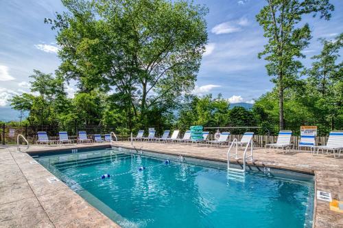 a swimming pool with chairs and blue chairs in it at Mountain Jewel, Game Room , Fire Pit, Theater Area, WIFI, Pool access!!! in Gatlinburg