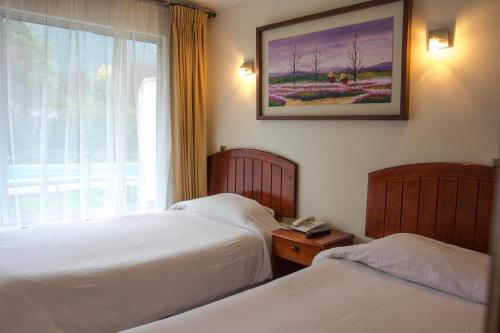 a hotel room with two beds and a window at Departamentos Parador de Darwin - Caja Los Andes in Valparaíso