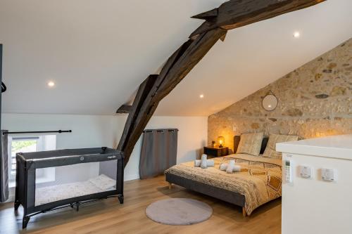 Le Loft Gîte de Dordogne في Mussidan: غرفة نوم بسرير وجدار حجري