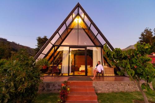 a man sitting on the porch of a glass house at Destinos Exclusivos Patate in Patate
