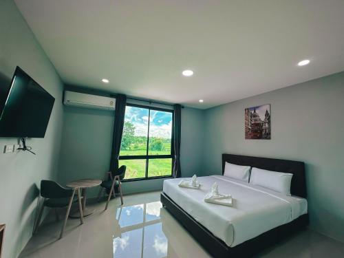a bedroom with a bed and a television and a table at Tuscany Hotel Buriram in Buriram