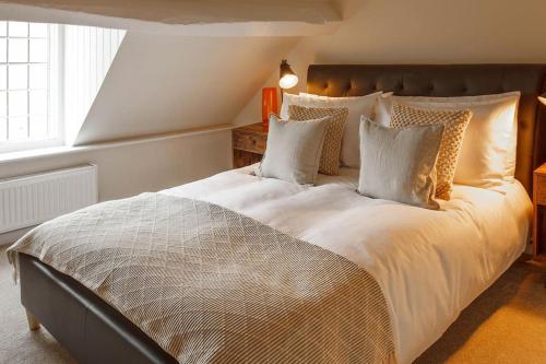 - une chambre dotée d'un grand lit avec des draps et des oreillers blancs dans l'établissement Stylish Painswick Getaway, à Painswick