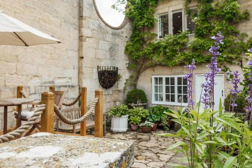a patio with a table and some plants and a building at Stylish Painswick Getaway in Painswick