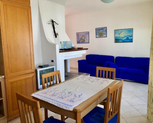 Una sala de estar con una mesa y un sofá azul. en Appartamento Vacanze Teulada, en Teulada