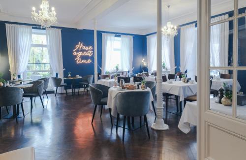 Hotel SONATA في بادن بادن: غرفة طعام مع طاولات وكراسي وجدران زرقاء