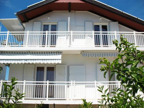 Casa blanca con balcones blancos y árboles en Apartments Niksa, en Petrčane