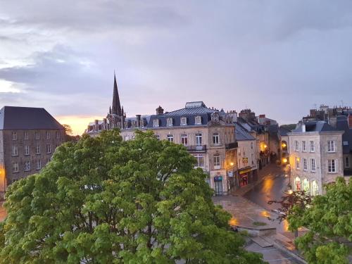 a view of a city at dusk with a church at Hôtel Le Vauban in Carentan