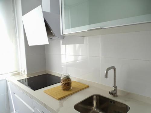 a kitchen counter with a sink and a glass on a cutting board at Apartamento con vistas a la Giralda. in Seville