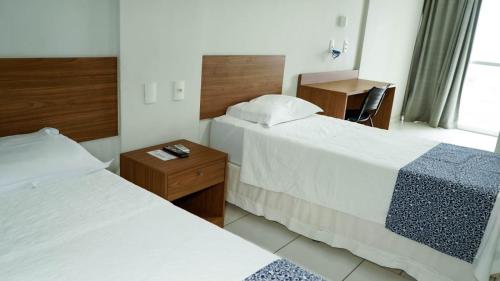 a hotel room with two beds and a desk at Hotel Arezzu in Linhares