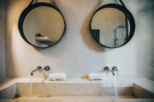 a bathroom with two mirrors and a sink with two faucets at Yum Kaax Boutique Villa in Tulum