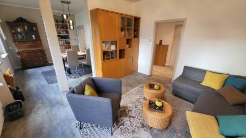 uma sala de estar com um sofá, cadeiras e uma mesa em Apartments am Saalebogen mit Gartenterrasse & Grillkamin, freie Parkplätze em Rudolstadt