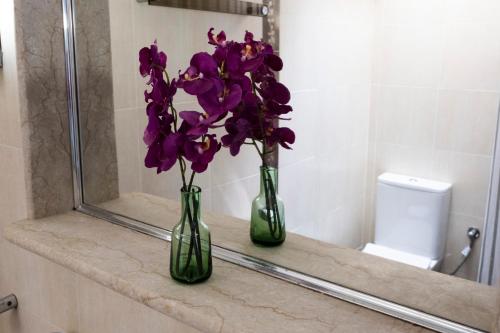 two vases with purple flowers on a counter in a bathroom at House 8 in Ermoupoli