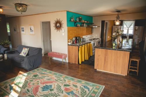 a living room with a couch and a kitchen at Auberge Mandala in Saint Mathieu Du Parc