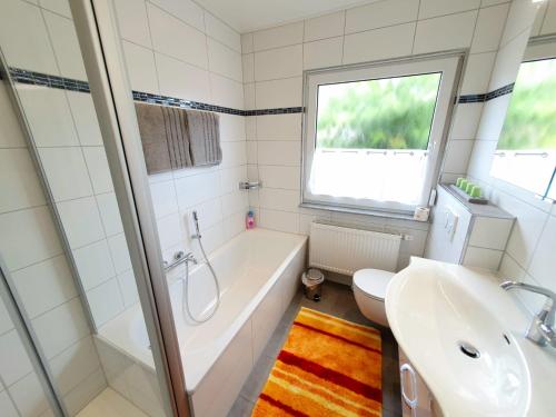 a bathroom with a tub and a toilet and a sink at Ferienhaus Regina im Bohnental in Lebach